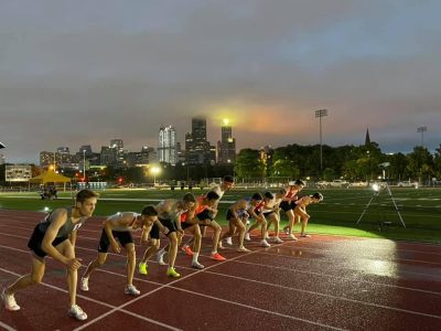 Group of young men on a track getting ready to begin a race.