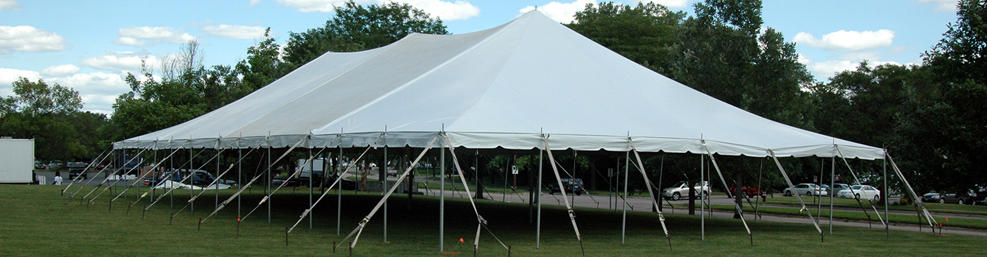 Large white tent set up outside with trees in the background.