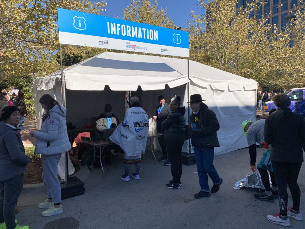 Several people standing around a 10' x 20' tent with sidewall set up outside.