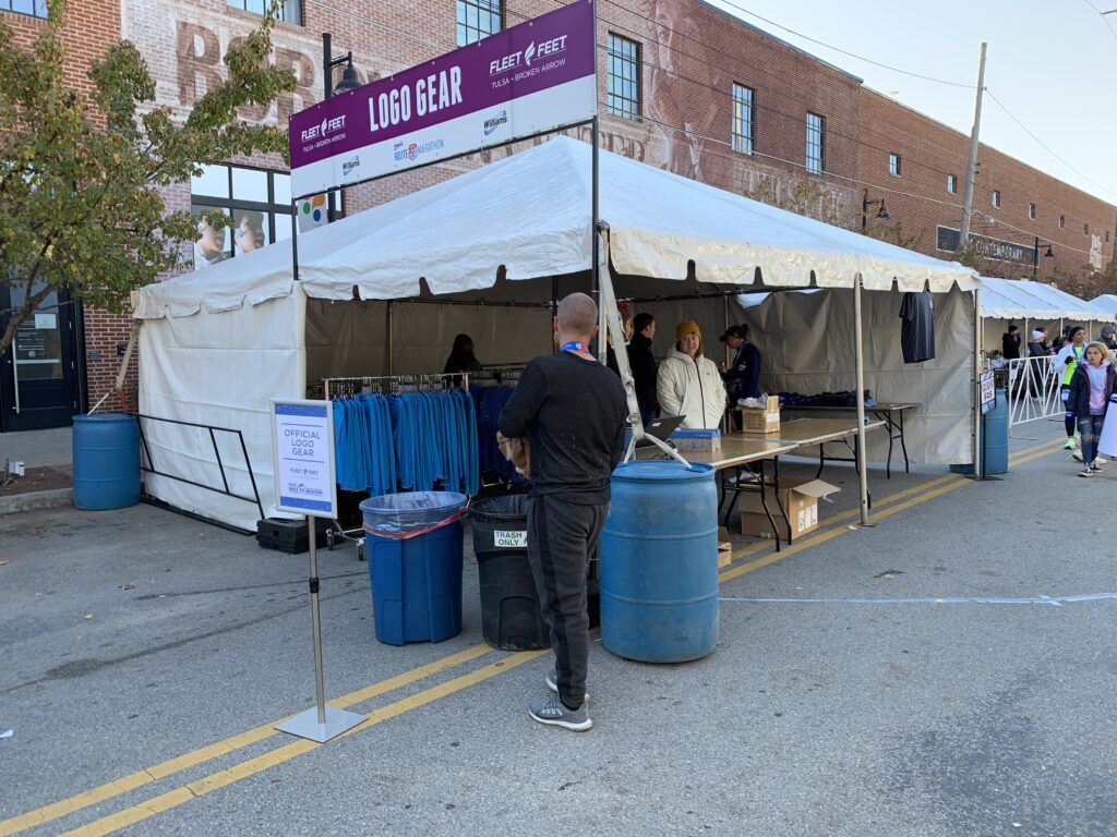 Several people standing under a 10' x 20' tent with sidewall set up outside.