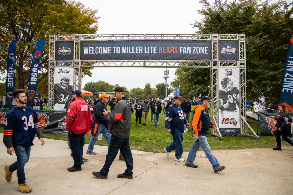 Many people around a truss structure that says, "Welcome to Miller Lite Bears Fan Zone."